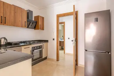 a kitchen with a stainless steel refrigerator and wooden cabinets at Urban Comfort - Pool - Netflix IPTV Parking in Marrakech
