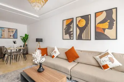 a living room with a couch and paintings on the wall at Urban Comfort - Pool - Netflix IPTV Parking in Marrakech