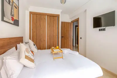 a bedroom with a white bed with a table on it at Urban Comfort - Pool - Netflix IPTV Parking in Marrakech