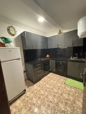 a kitchen with gray cabinets and a white refrigerator at Appartement cosy avec 2 terrasses in Marrakech