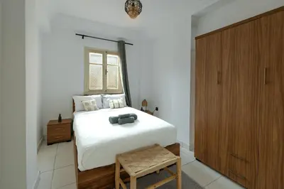a bedroom with a white bed and a wooden cabinet at Appartement yasmina in Marrakech
