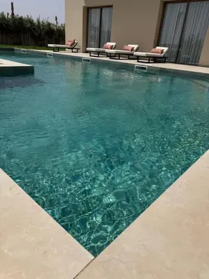 a swimming pool with blue water in a building at Villa Zeytoune sans vis à vis in Marrakech