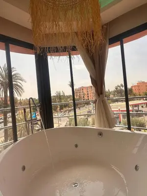 a bath tub in a room with a large window at Central nest romantic stay in Marrakech