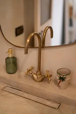 a bathroom sink with a brass faucet and a mirror at Riad Le Terracotta in Marrakech