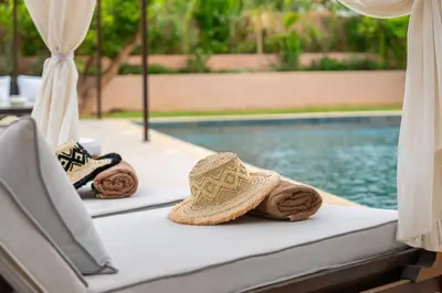 a pair of straw hats sitting on a table next to a swimming pool at Villa Dar Al Jaddah, Luxury and Refinement in Marrakech