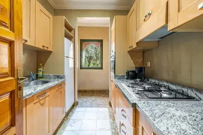 a kitchen with wooden cabinets and granite counter tops at La Palmeraie 2BR Garden & Pool in Marrakech