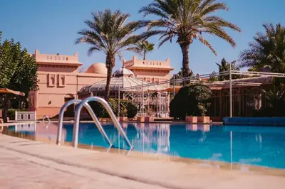 a swimming pool in front of a building with palm trees at La Palmeraie 2BR Garden & Pool in Marrakech