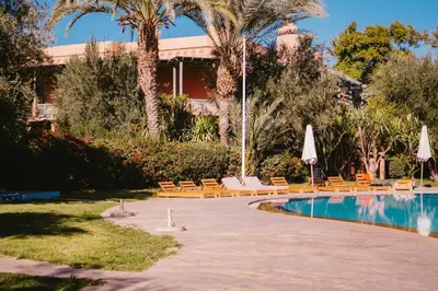 a resort with a swimming pool with chairs and umbrellas at La Palmeraie 2BR Garden & Pool in Marrakech