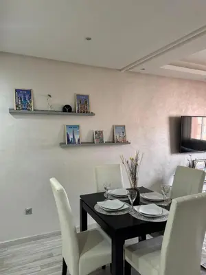 a dining room with a black table and white chairs at Appartement moderne proximité Carré Eden Marrakech in Marrakech