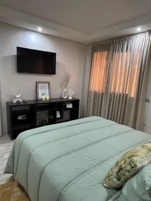 a bedroom with a bed with a television on the wall at Appartement moderne proximité Carré Eden Marrakech in Marrakech