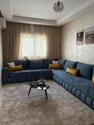 a living room with a blue couch and a table at Appartement refait à neuf in Marrakech