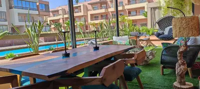 a wooden table and chairs on a patio with a pool at Whispers of NATURE in Marrakech