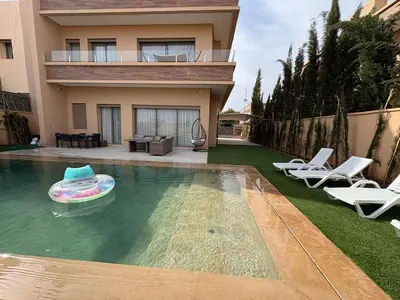 a house with a pool with a frisbee in the water at Villa del Sur 5 min du centre in Marrakech