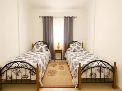 two beds in a room with a window at Bright 2-BR - Balcony & Parking - Fast Wi-Fi - Near Route de Casa in Marrakech