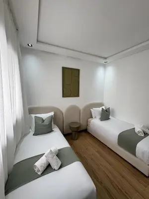 two beds in a room with white walls at Menara Garden - 3 Ch - Piscine - 2 min de M Avenue in Marrakech