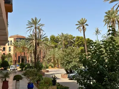 a parking lot with palm trees and a car at Appartement de Luxe avec Piscine et Jacuzzi Marrakech in Marrakech