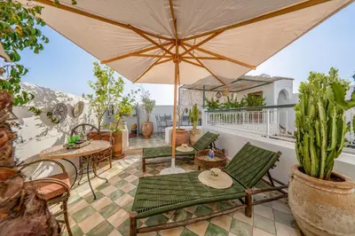 a patio with chairs and tables and an umbrella at Riad Dar Amani in Marrakech
