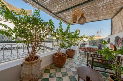 a balcony with potted plants and tables and chairs at Riad Dar Amani in Marrakech