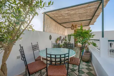 a patio with a glass table and chairs at Riad Dar Amani in Marrakech