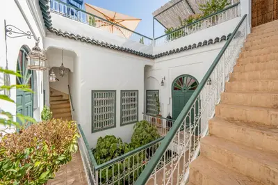a staircase leading up to a white house with green doors at Riad Dar Amani in Marrakech