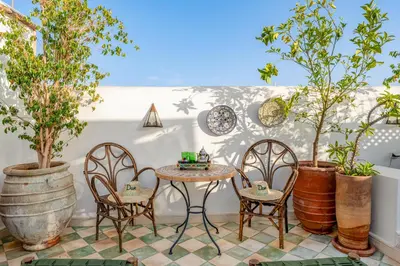 a patio with a table and chairs and trees at Riad Dar Amani in Marrakech