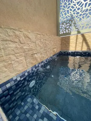 a swimming pool with a tiled floor and a window at Dar Diaft'na in Marrakech