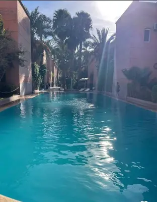 a swimming pool with a waterfall and palm trees at Dar wafa in Marrakech