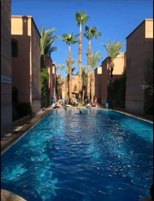 a swimming pool with palm trees in a resort at Dar wafa in Marrakech