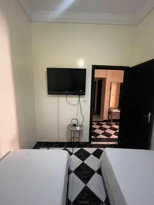 a bedroom with two beds and a flat screen tv at Dar wafa in Marrakech