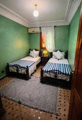 two beds in a room with green walls at Très bel Riad avec piscine au cœur de Marrakech in Marrakech