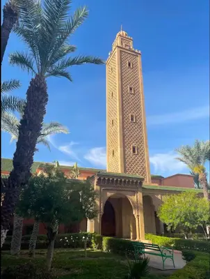 a building with a clock tower with a palm tree at Authentic Moroccan Riad with a pool and a rooftop in Marrakech
