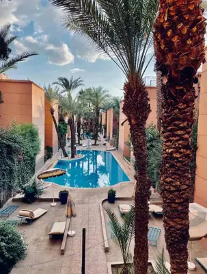 a pool in a resort with palm trees at Authentic Moroccan Riad with a pool and a rooftop in Marrakech