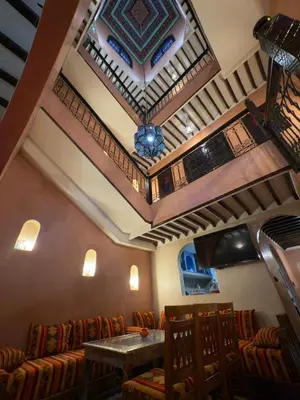 a restaurant with a table and chairs and a ceiling at Authentic Moroccan Riad with a pool and a rooftop in Marrakech