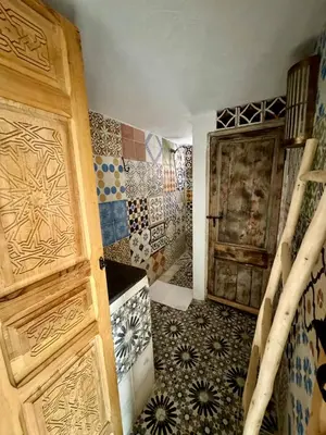a bathroom with a door and a room with tiles at Riad Dar Familya in Marrakech