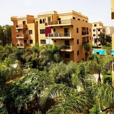 an apartment building with palm trees in front of it at Studio cosy Centre ville à 4 min et stade à 6 min in Marrakech