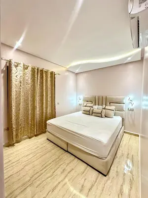 a white bedroom with a large bed with white sheets and pillows at Séjournez dans un appart moderne, calme et tout équipé à Marrakech in Marrakech