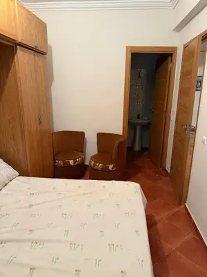 a bedroom with a bed and two chairs in a room at The cozy Den in Marrakech
