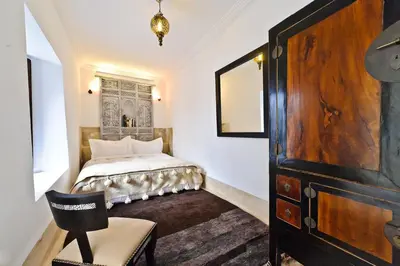 a bedroom with a bed and a chair and a dresser at Riad Porte Royale in Marrakech