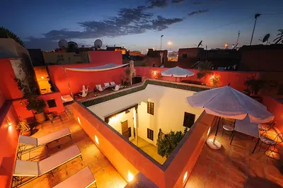 an outdoor patio with tables and umbrellas at night at Riad Porte Royale in Marrakech