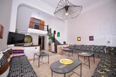 a living room with couches and tables and a tv at Le riad de Daba in Marrakech