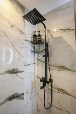 a shower head in a bathroom with marble walls at Luxury Designer Apartment Central Marrakech in Marrakech