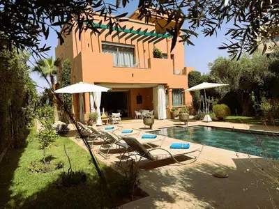 a house with a swimming pool with chairs and umbrellas at Villa Marrazen, lovely villa -housestaff included in Marrakech