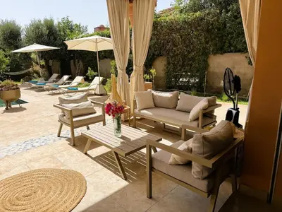 a patio with couches and tables and umbrellas at Villa Marrazen, lovely villa -housestaff included in Marrakech