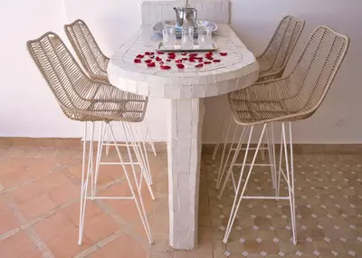 a white table with chairs and a table with roses on it at Dar Farah Riad luxe privé, 3ch, piscine chauffée, ptit déj in Marrakech