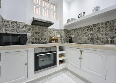 a kitchen with white cabinets and a microwave at Dar Farah Riad luxe privé, 3ch, piscine chauffée, ptit déj in Marrakech