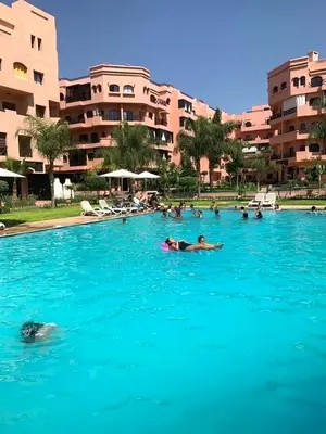 a group of people swimming in a large swimming pool at Chez Mams Guest House - Private Rooms in a Resort-Style Apartment Complex in Marrakech