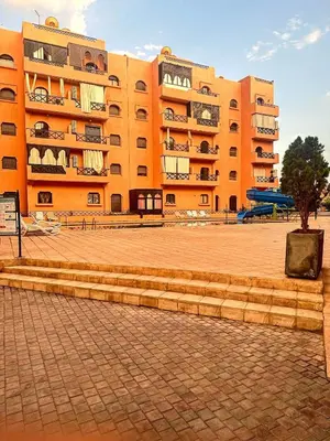a large orange building with a tree in front of it at Chez Mams Guest House - Private Rooms in a Resort-Style Apartment Complex in Marrakech