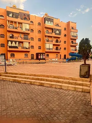 a large orange building with a tree in front of it at Chez Mams Guest House - Private Rooms in a Resort-Style Apartment Complex in Marrakech