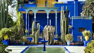 a blue building with a fountain and cactuses in front at Le Nomadic Chic Piscine Privée in Marrakech
