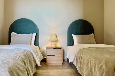 two beds with green headboards next to a night stand with a lamp at Apartment in Agdal with Pool and Terrace in Marrakech